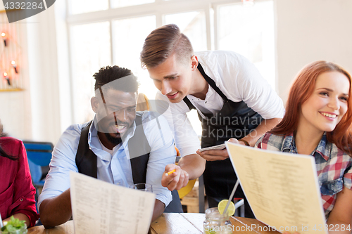 Image of waiter and friends with menu and drinks at bar