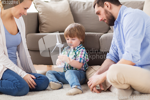 Image of happy family playing with toy wind turbine
