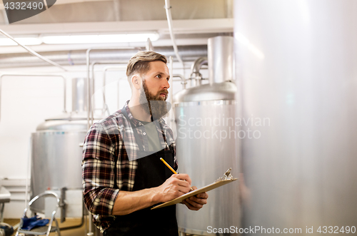 Image of man with clipboard at craft brewery or beer plant