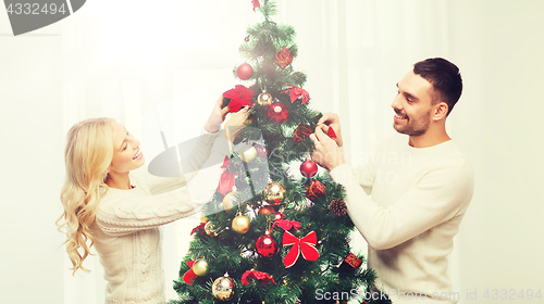 Image of happy couple decorating christmas tree at home