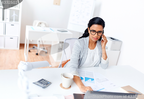 Image of businesswoman calling on smartphone at office