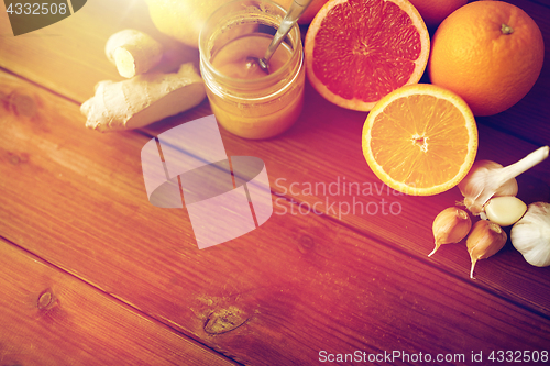 Image of honey, citrus fruits, ginger and garlic on wood