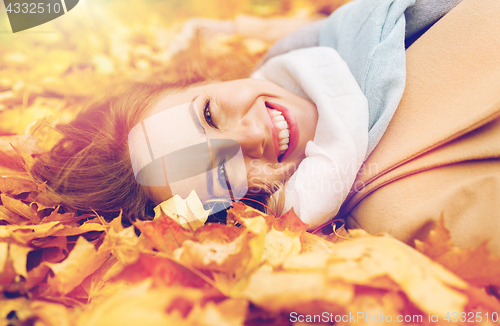 Image of beautiful happy woman lying on autumn leaves