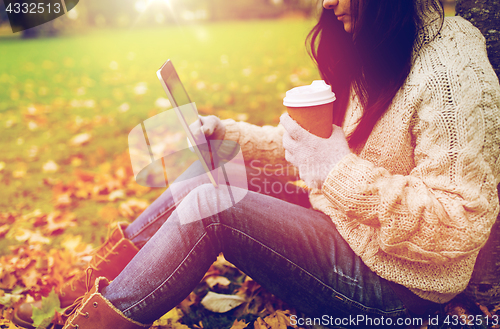 Image of woman with tablet pc and coffee in autumn park