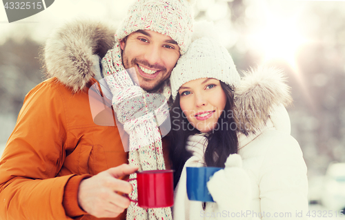 Image of happy couple with tea cups over winter landscape