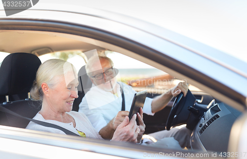 Image of happy senior couple with tablet pc driving in car