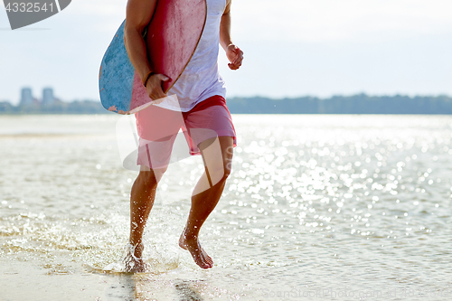 Image of happy young man with skimboard on summer beach