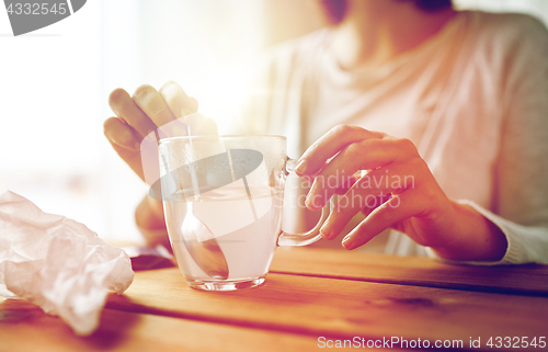 Image of woman stirring medication in cup with spoon