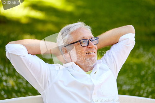 Image of happy senior man in glasses sitting at summer park