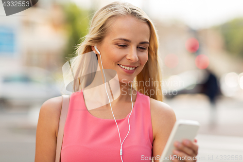 Image of happy young woman with smartphone and earphones