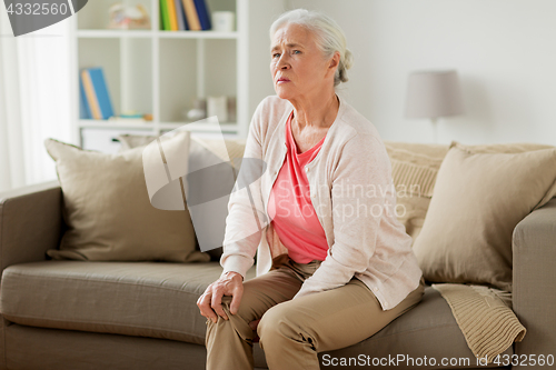 Image of senior woman suffering from pain in leg at home