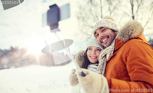 Image of happy couple taking selfie by smartphone in winter