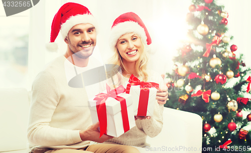 Image of happy couple at home with christmas gift boxes
