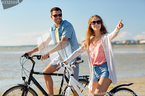 Image of happy young couple riding bicycles at seaside