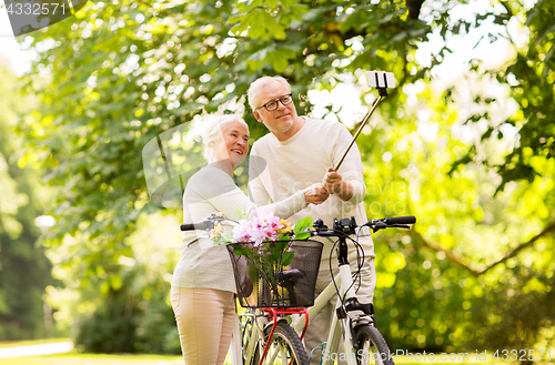 Image of senior couple with bicycles taking selfie at park