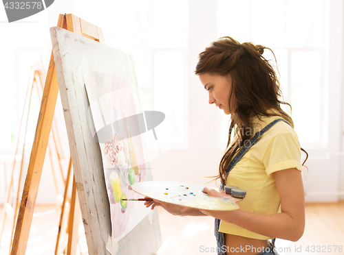 Image of student girl with easel painting at art school