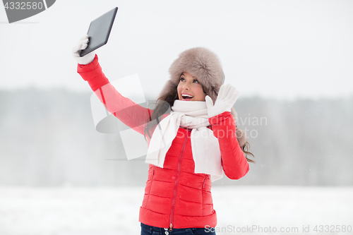 Image of woman in winter fur hat with tablet pc outdoors