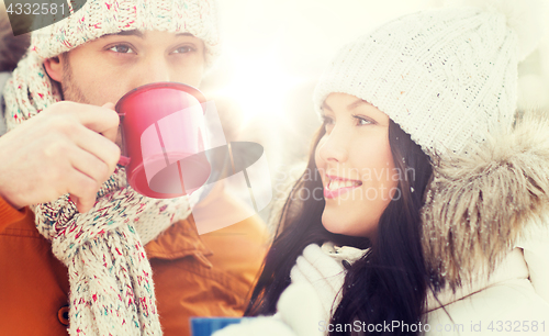 Image of happy couple with tea cups over winter landscape