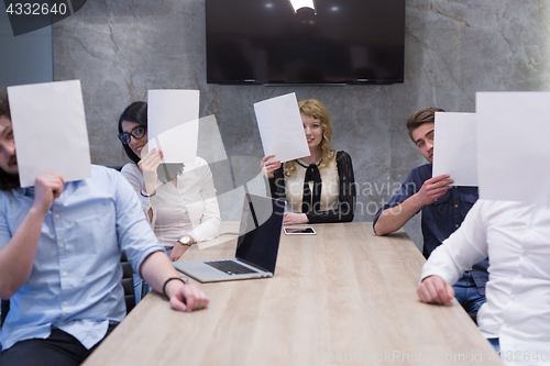 Image of startup business team holding a white paper over face