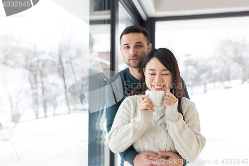 Image of multiethnic couple enjoying morning coffee by the window