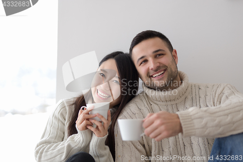 Image of multiethnic couple enjoying morning coffee by the window