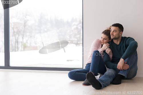 Image of young couple sitting on the floor near window at home