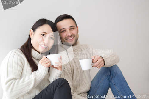 Image of multiethnic couple enjoying morning coffee by the window