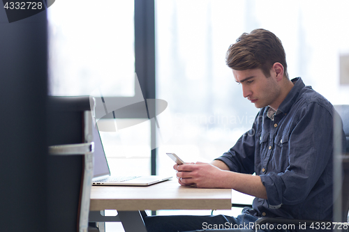 Image of Young casual businessman using smartphone