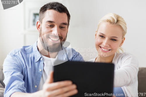Image of smiling happy couple with tablet pc at home