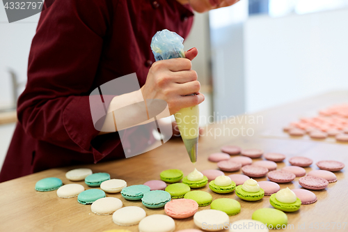 Image of chef with injector squeezing filling to macarons