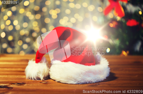 Image of close up of santa hat on wooden table over lights