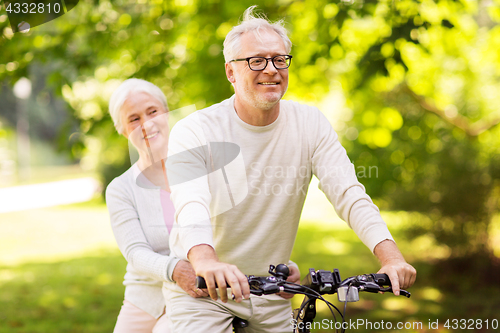 Image of happy senior couple riding bicycle at park