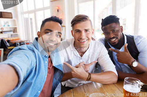 Image of friends taking selfie and drinking beer at bar