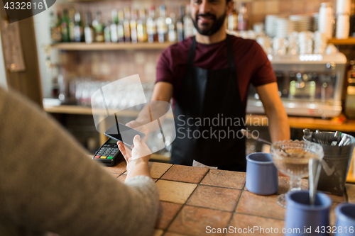 Image of man with payment terminal and hand with smartphone