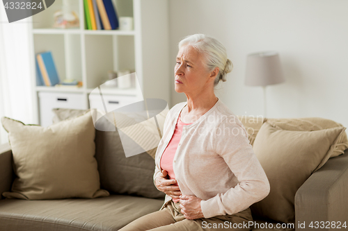 Image of senior woman suffering from stomach ache at home