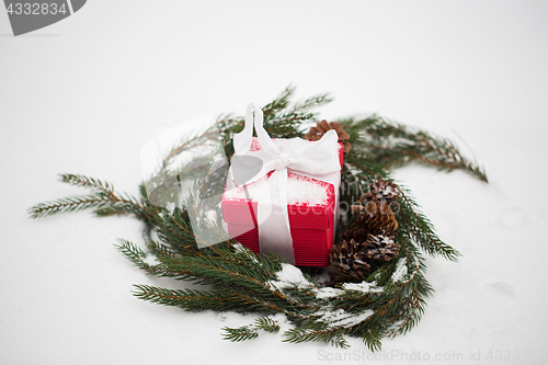 Image of christmas gift and fir wreath with cones on snow