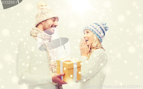 Image of smiling couple in winter clothes with gift box