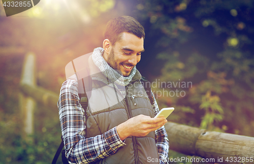 Image of happy man with backpack and smartphone outdoors