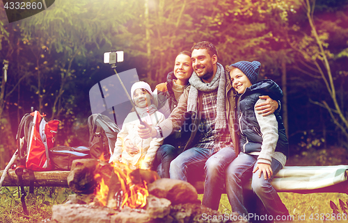 Image of family with smartphone taking selfie near campfire