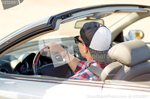 Image of happy young man in shades driving convertible car