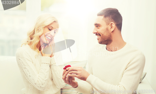 Image of happy man giving engagement ring to woman at home