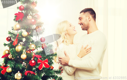 Image of happy couple hugging near christmas tree at home