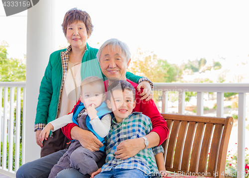 Image of Senior Adult Chinese Couple Sitting With Their Mixed Race Grandc