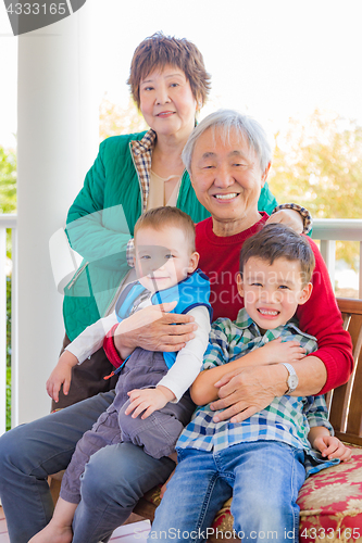 Image of Senior Adult Chinese Couple Sitting With Their Mixed Race Grandc