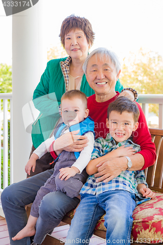 Image of Senior Adult Chinese Couple Sitting With Their Mixed Race Grandc