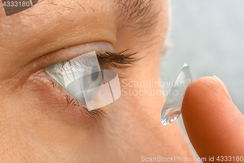 Image of closeup of woman putting contact lens in her eye