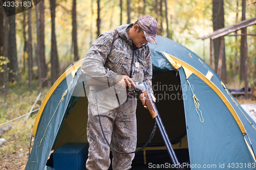 Image of hunter loading shotgun in the hunting camp