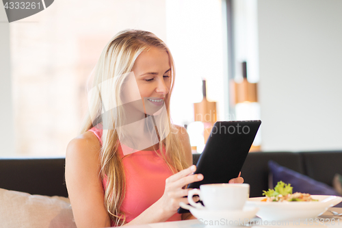 Image of happy young woman with tablet pc at restaurant