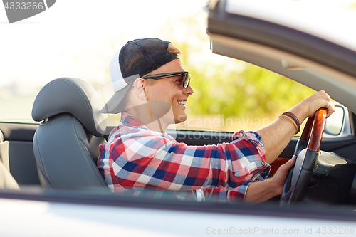 Image of happy young man in shades driving convertible car