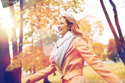 Image of beautiful happy young woman walking in autumn park